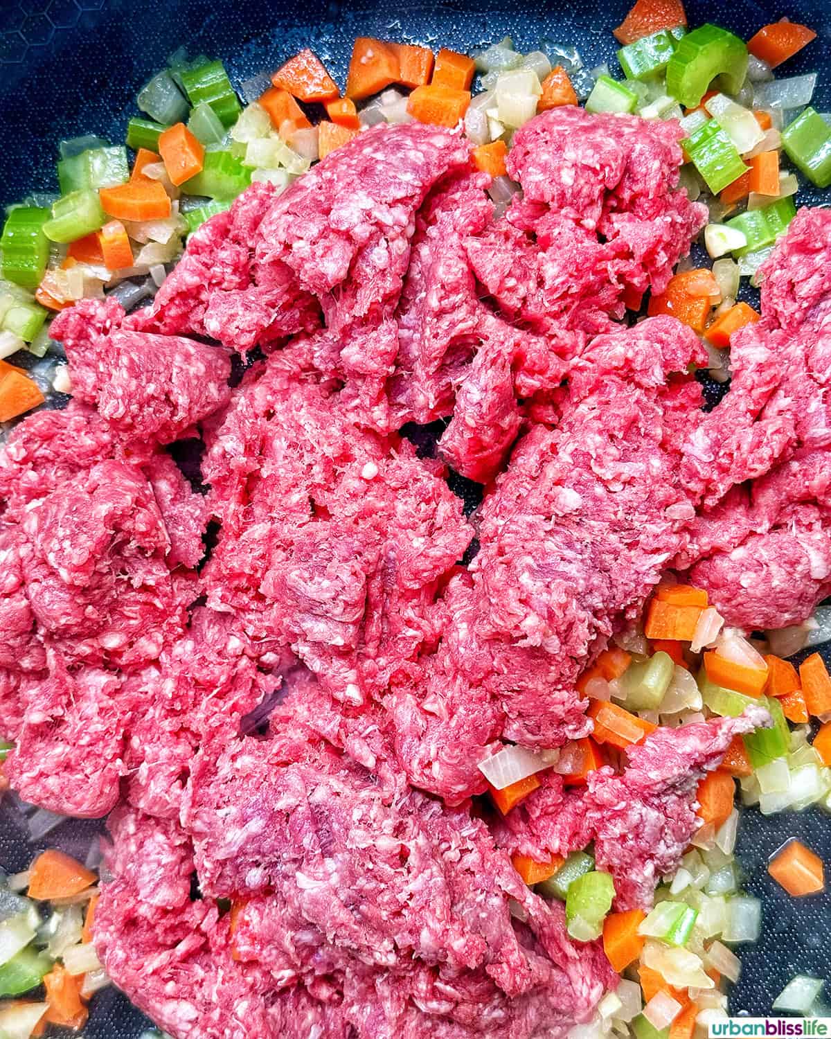 meat added to celery, carrots, onions, garlic to make baked pasta bolognese.