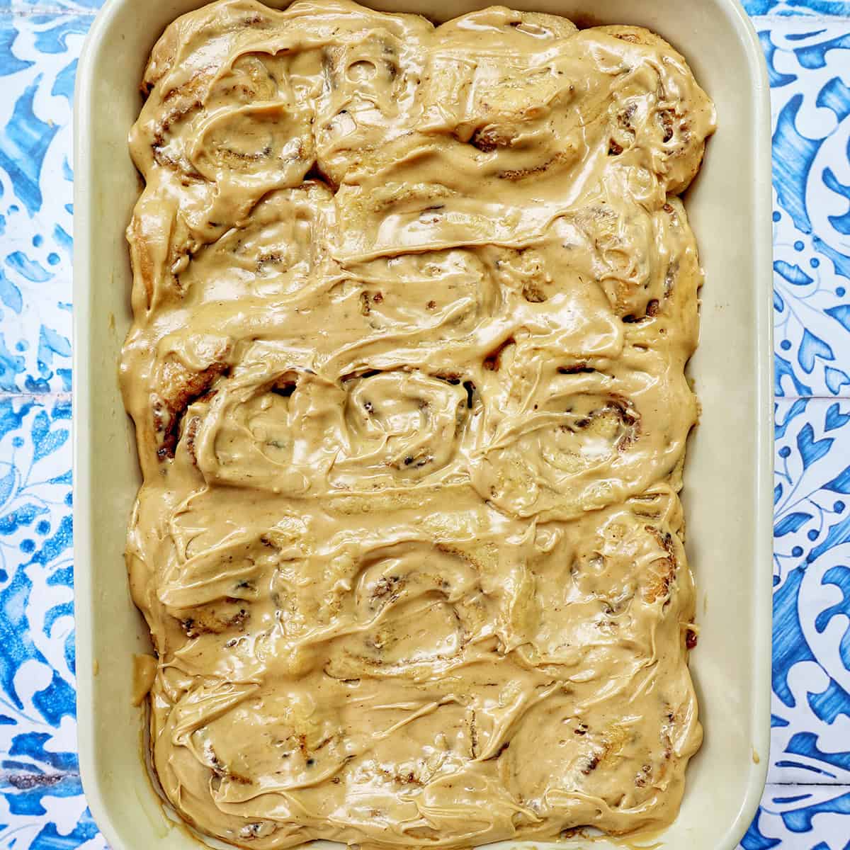 baking dish with coffee cinnamon rolls against a blue and white French backdrop.