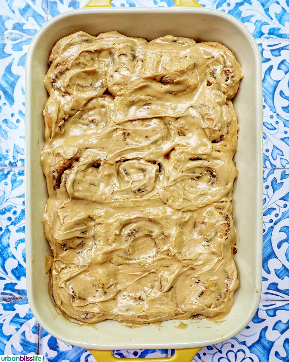 baking dish with coffee cinnamon rolls against a blue and white French backdrop.