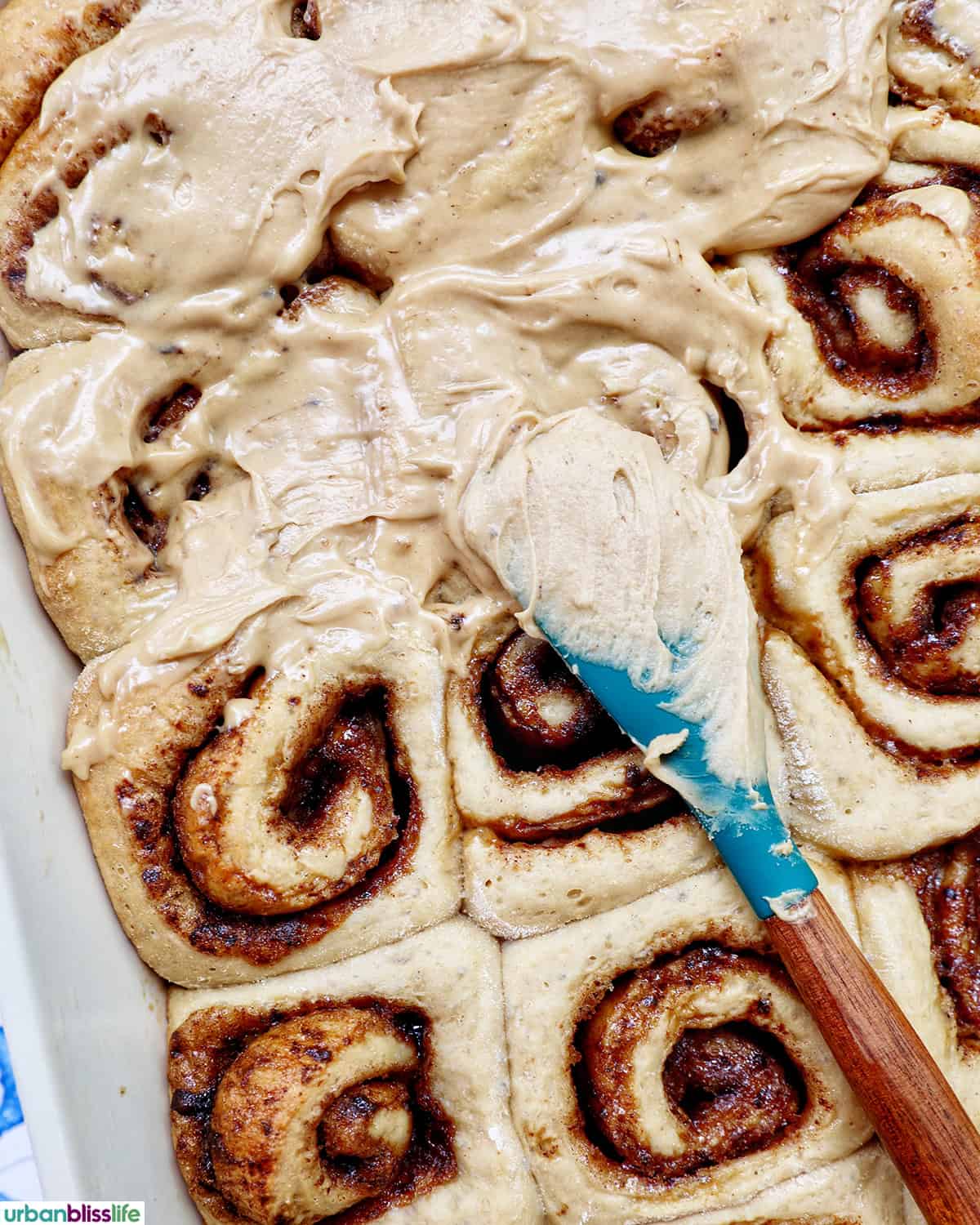 spreading frosting on top of coffee cinnamon rolls just baked.