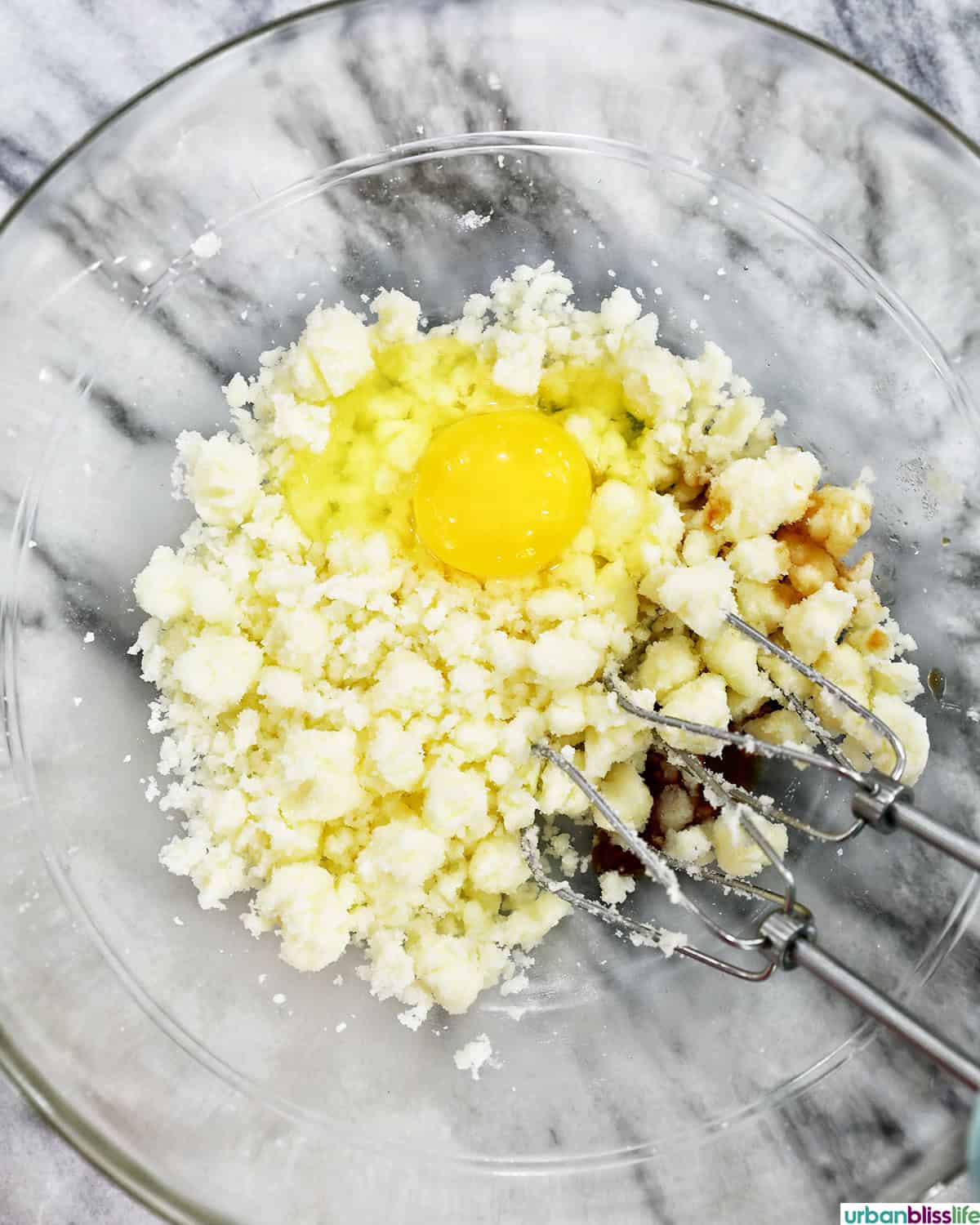 egg and vanilla added to butter and sugar in a bowl.