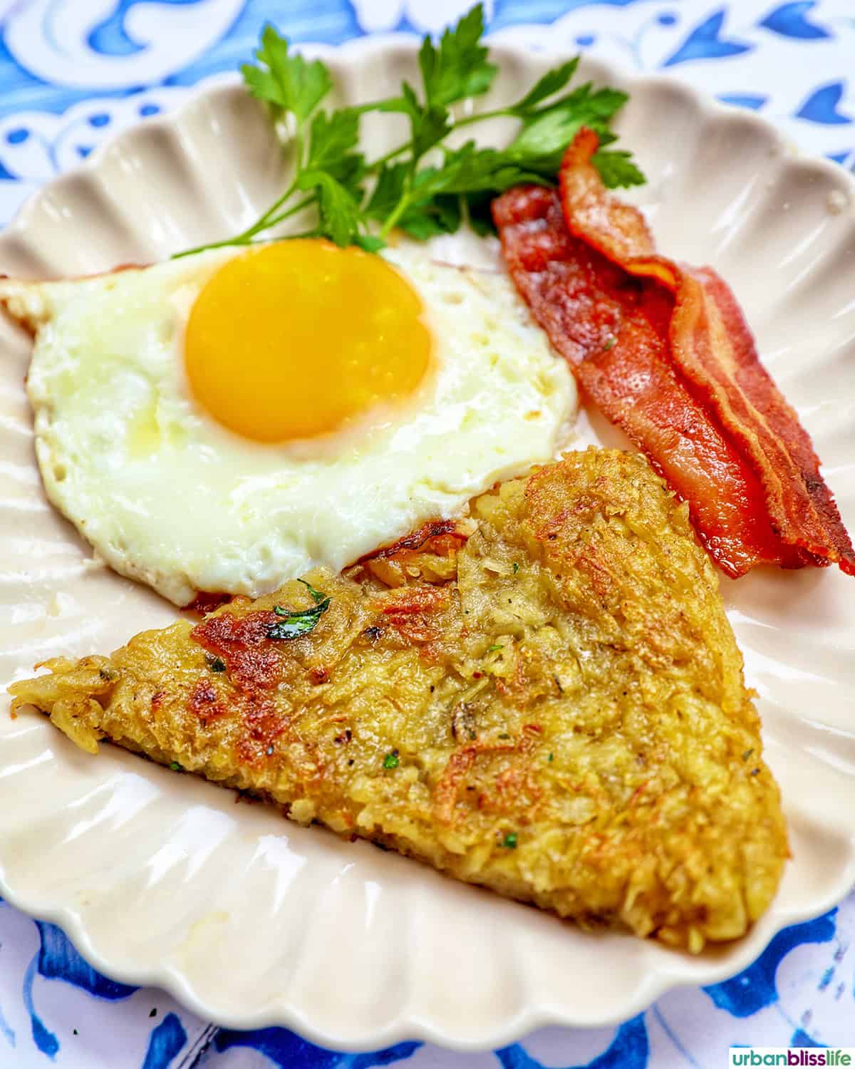 eggs, bacon, and slice of swiss rosti on a plate with parsley garnish.