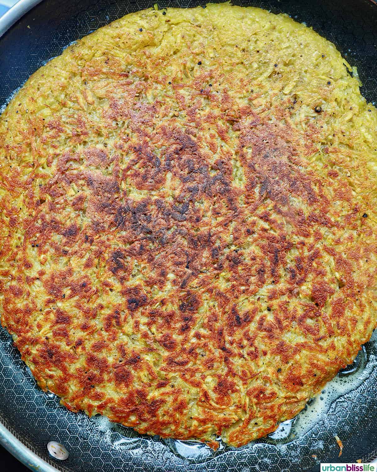 grated potatoes in a pan to make Swiss rosti.