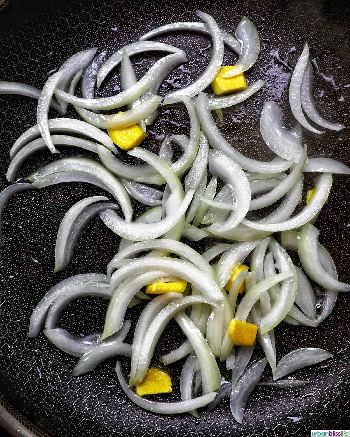 onions and ginger slices cooking in a pan.