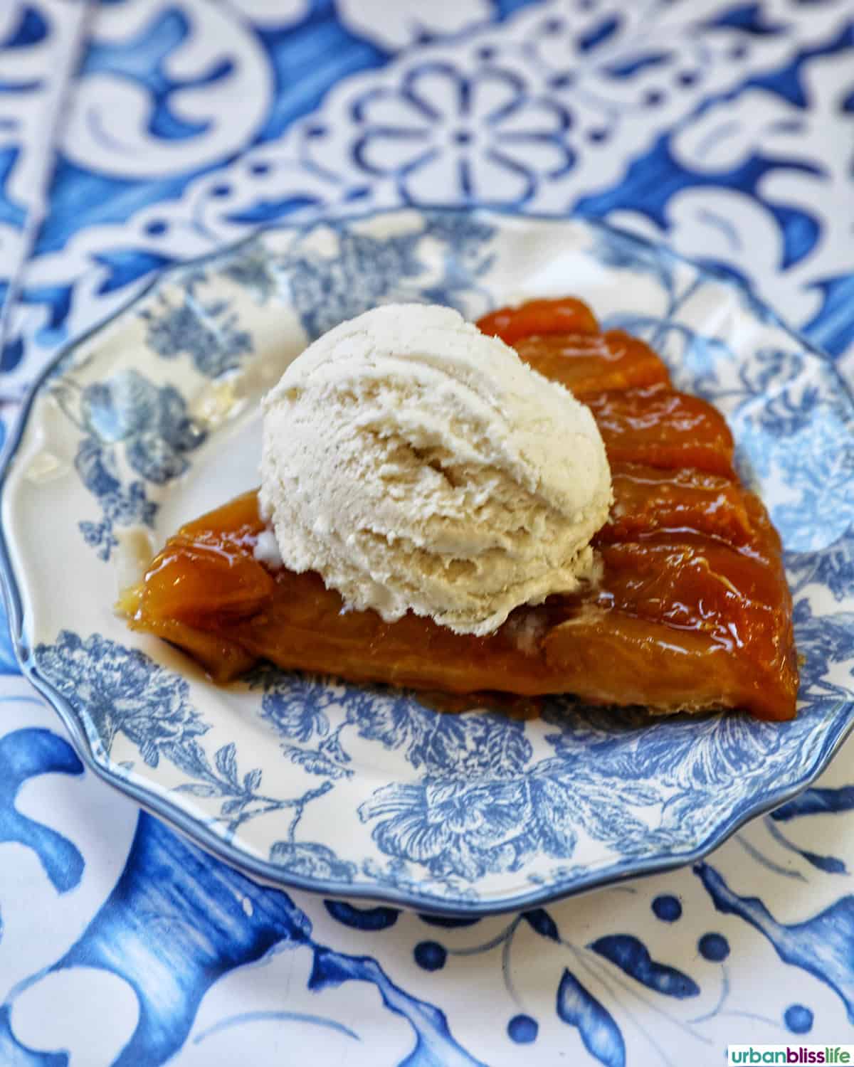 slice of pomme tarte tatin with a scoop of vanilla ice cream on top.