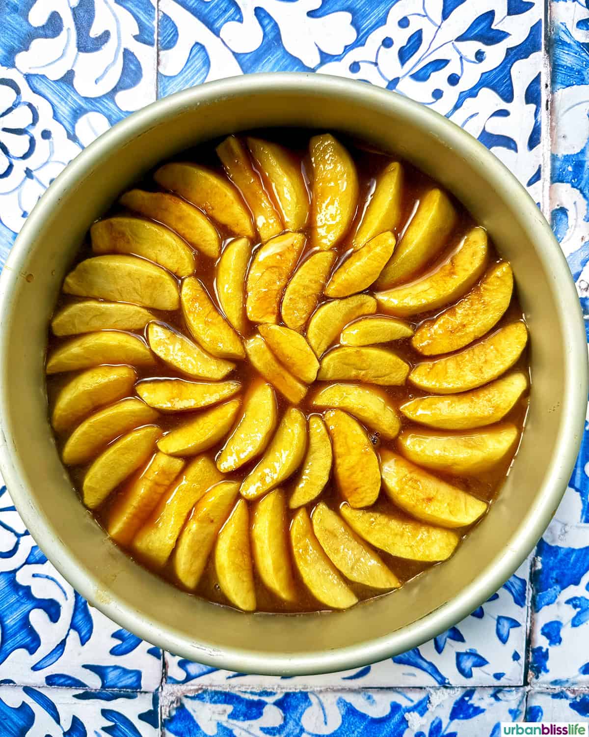 caramelized apple slices placed in a circular pattern in a cake pan.