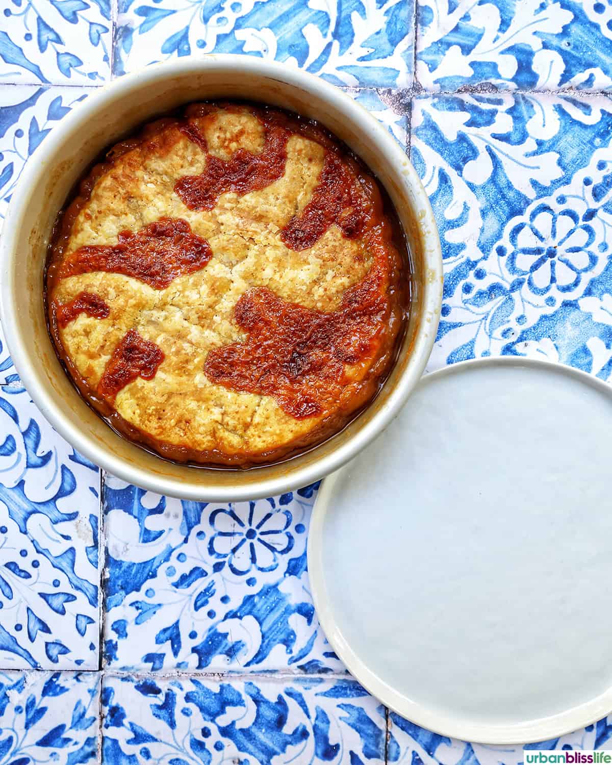 baked pomme tarte tatin upside down next to a white plate.