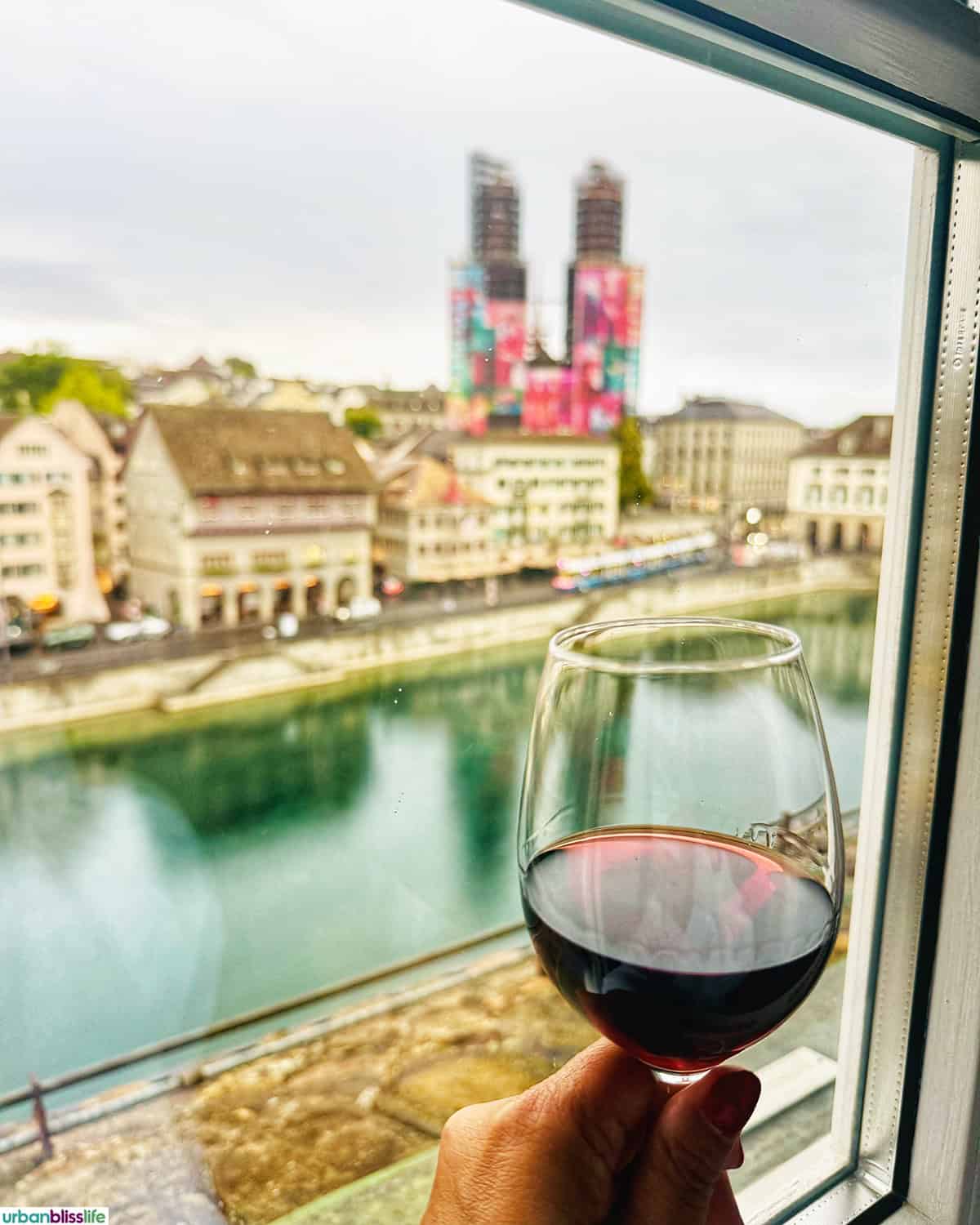 wine glass next to river view from a room at Hotel Storchen Zürich.